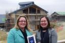Tamsin Lewis, new head of care for Little Harbour, is given the books by Cornwall College lecturer Anne-Marie Young in front of the partially built new hospice.