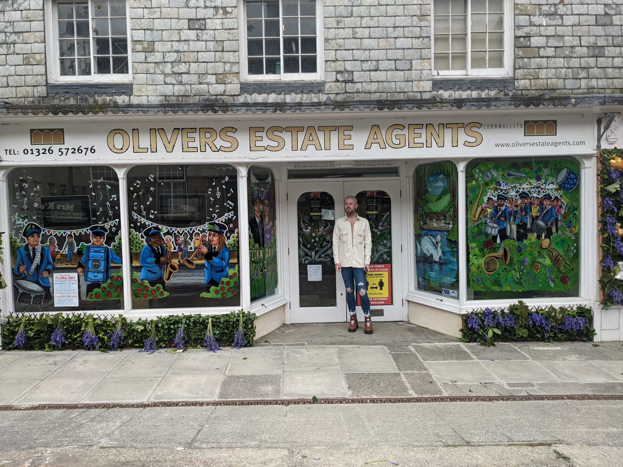Mike Prowse outside Olivers Estate agents with his window painting. 