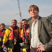 Looe RNLI volunteer crew Jack Spree, David Jackman, Goron Jones and Aaron Rix with Kris Marshall on East Looe Quay during filming