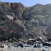 The scale of the rock falls at Trevaunance Cove can be seen when compared to the size of the warning sign bottom right