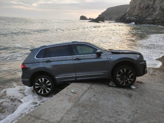 The vehicle perched on the edge of a wall before the waves engulfed it. Picture: St Agnes Coastguard