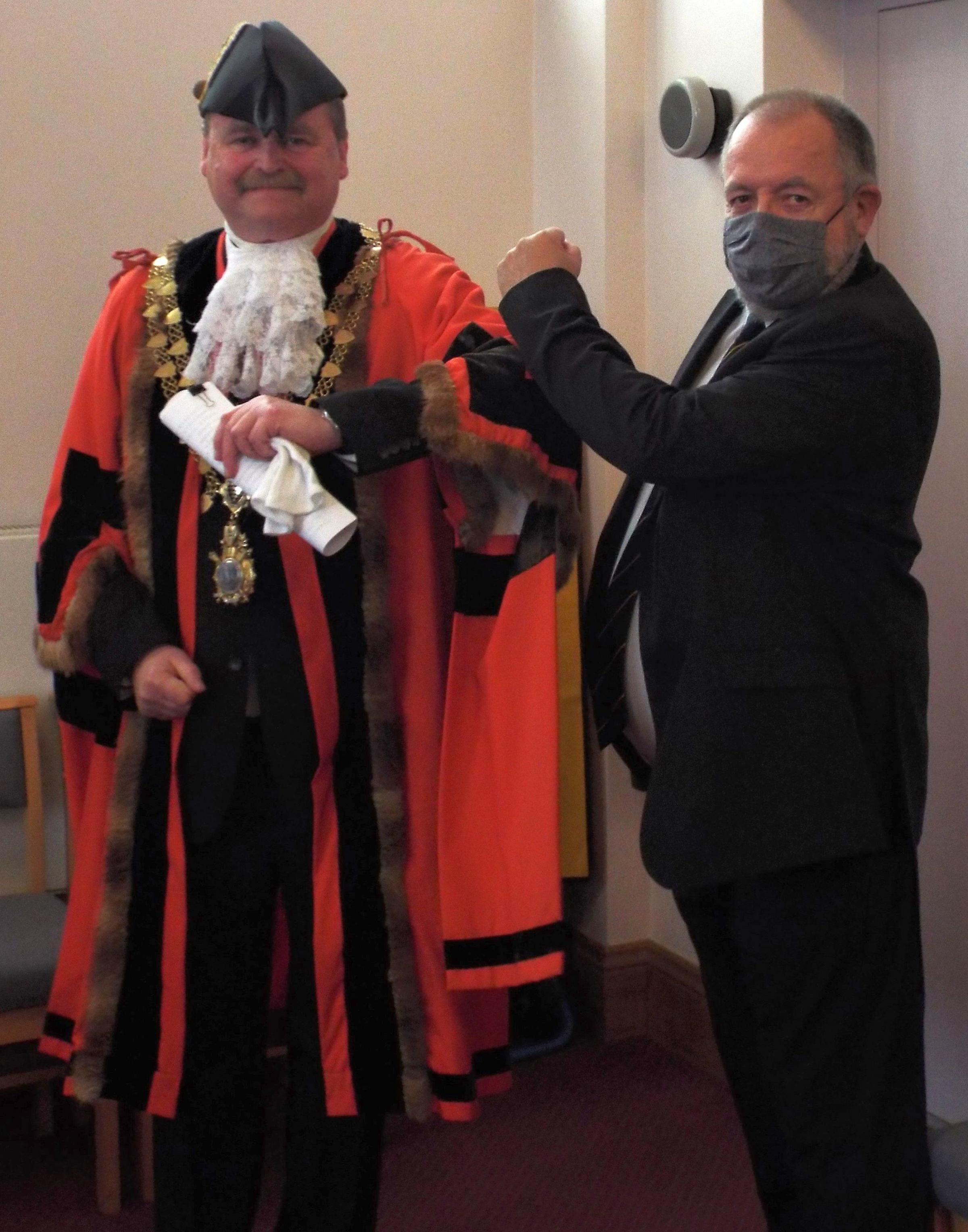 New Helston mayor Tim Grattan-Kane is given a Covid-friendly arm bump by retiring mayor John Martin Picture: Peter Lavelle