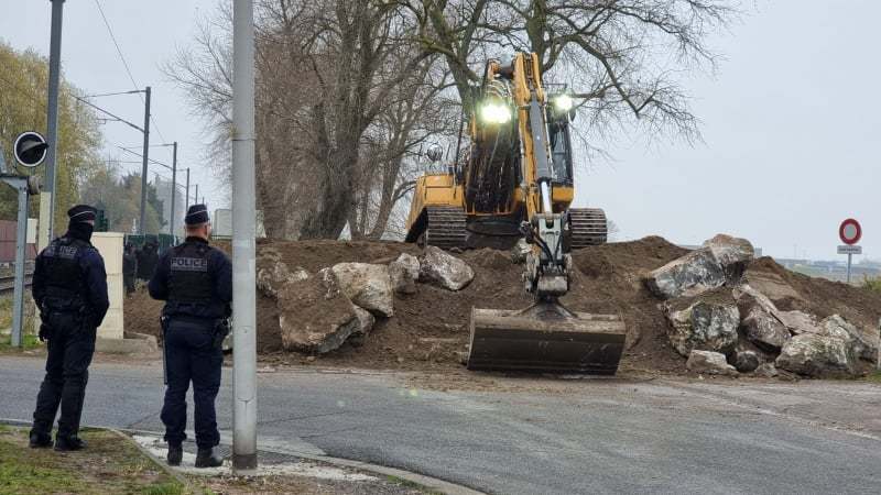 French Police watch as a wall is built round one of the camps 
