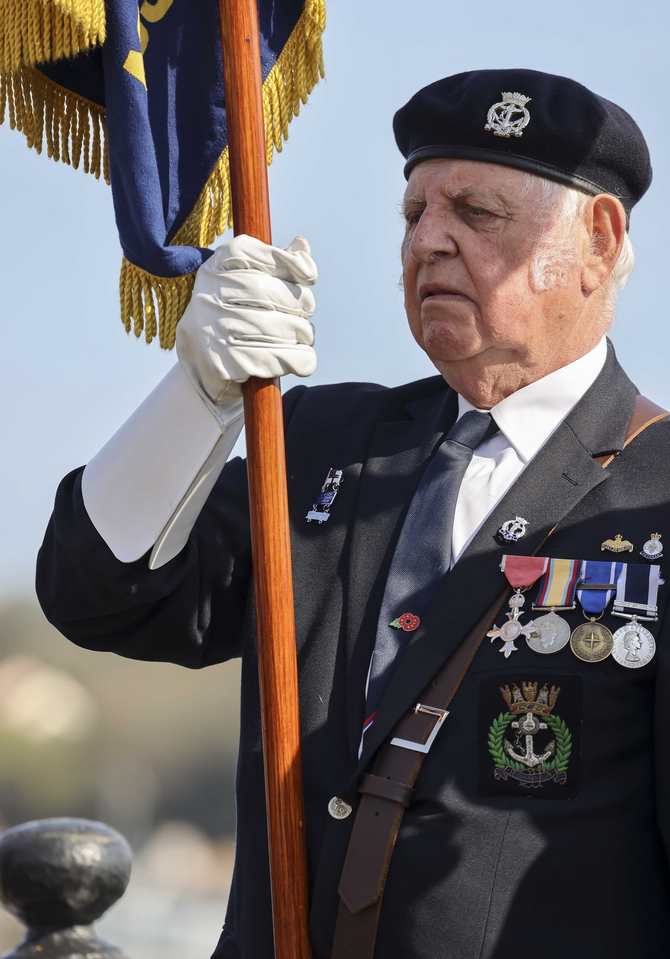 A Standard Bearer shoulders the flag during a service held on the Prince of Wales Pier marking the 80th anniversary of the St Nazaire raid. Credit: LPhot Dan Rosenbaum, RNAS Yeovilton