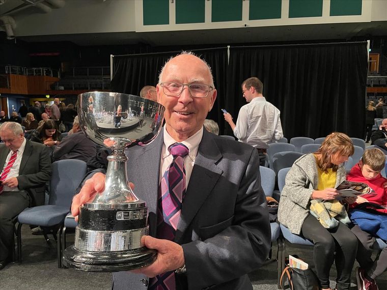 John Berryman, the band’s Professional Conductor and a remarkable 82 years young, displays the trophy. 