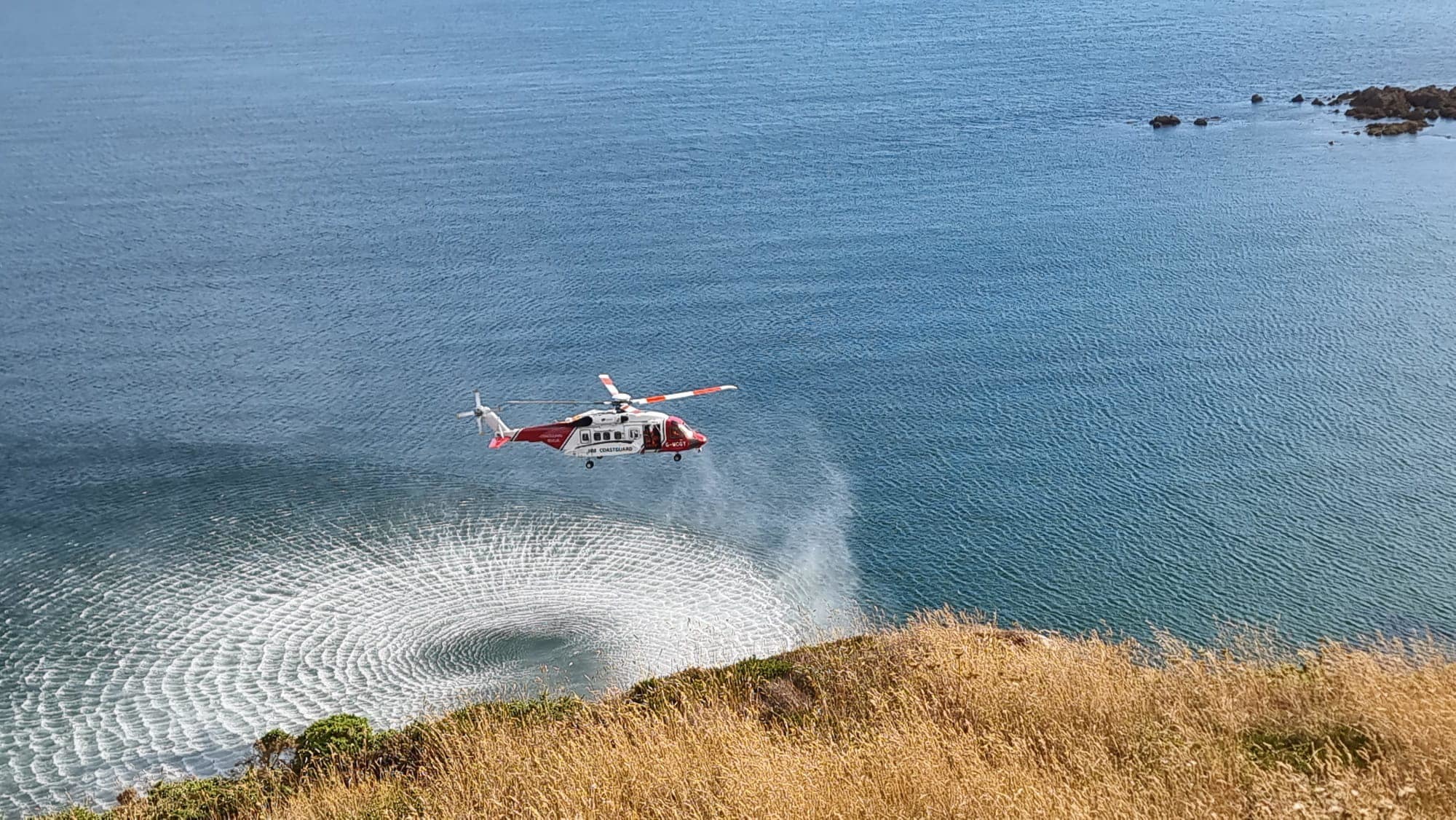 The helicopter prepares to winch the climber from the cliff  Picture: Mullion Coastguard