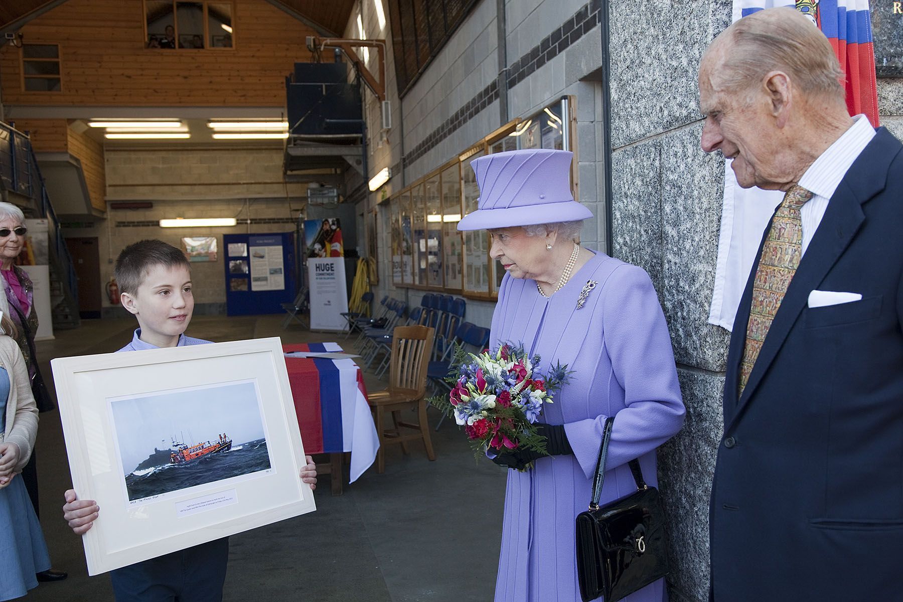 Lifeboatman Scott Perkins son William Perkin presents a picture to the Queen and Prince Philip.