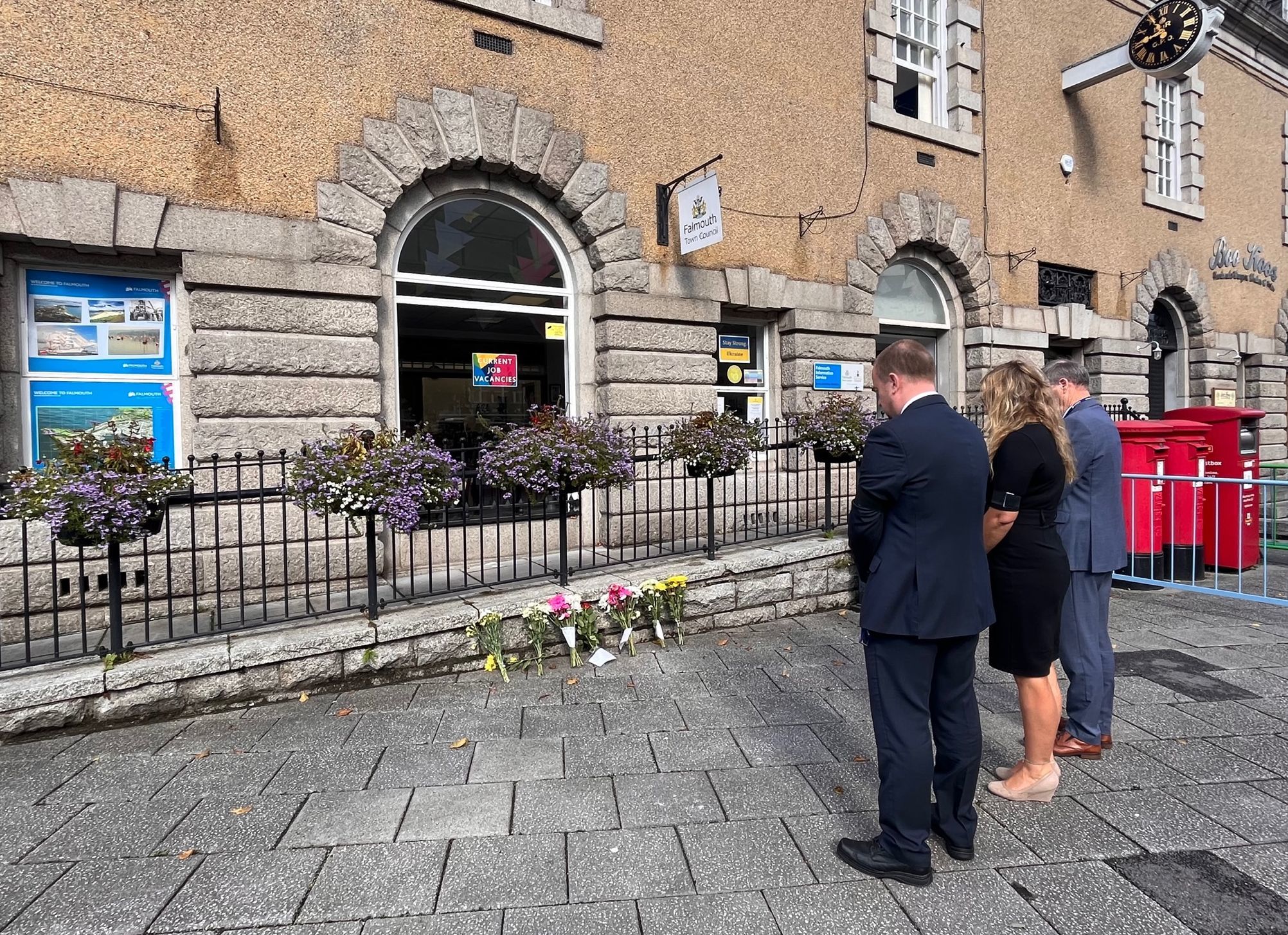 Town centre manager Richard Gates, deputy mayor Kirstie Edwards and mayor Steven Eva leave their floral tributes on Friday