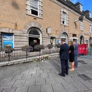 Town manager Richard Gates, Deputy Mayor Kirstie Edwards and Mayor of Falmouth Steve Eva pay their respects to the Queen next to floral tributes outside Falmouth Town Council's offices