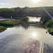 The road past Poldhu Beach flooded on Tuesday lunchtime