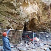 A protestor points to what they say are cracks in Whipsiderry Cliffs as work goes on in the cave