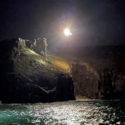 The coastguard helicopter flies over the cliffs near Rinsey to rescue a fallen climber