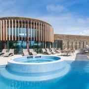 Outdoor heated sunset spa encircled by an edge pool at AquaClub at The Headland Hotel & Spa