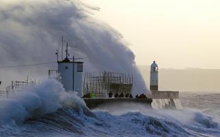 Waves crash against the sea wall and Porthcawl Lighthouse in Porthcawl, Bridgend, Wales, as Storm Eunice hits the south coast. Photo via PA.